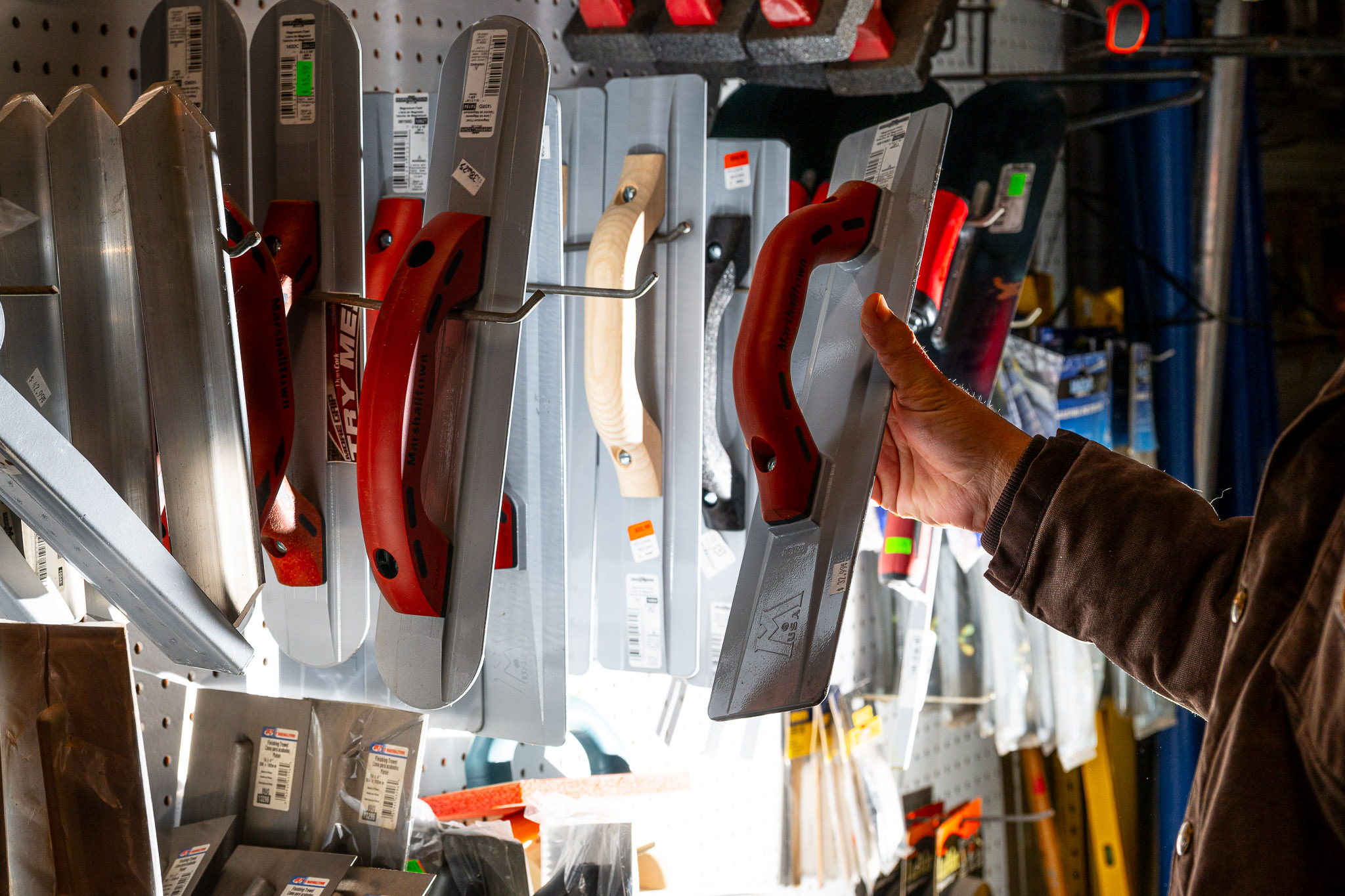 A man's hand lifts an item off a rack in a hardware store.